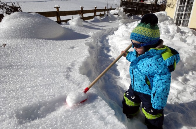 Kind spielt im Schnee im tief verschneiten Flachau